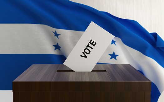 Honduras presidential and legislative elections concept. A vote envelope is entering into a ballot box. Ballot box is in front of a waving Honduras flag and it is made of wood. Horizontal composition with copy space. Great use for referendum and elections related concepts.